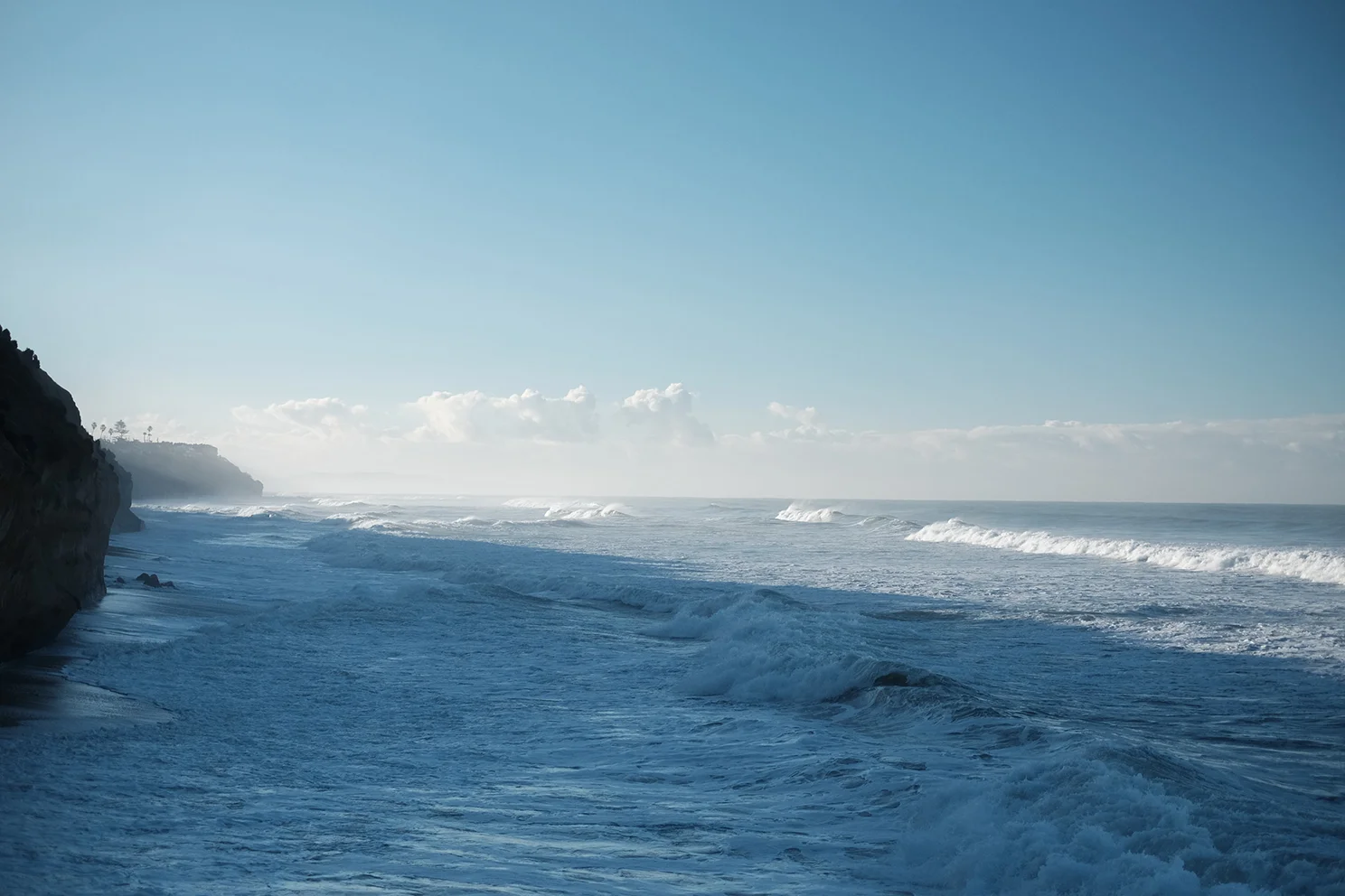 Ocean lapping sandstone cliffs at high tide in Encinitas.